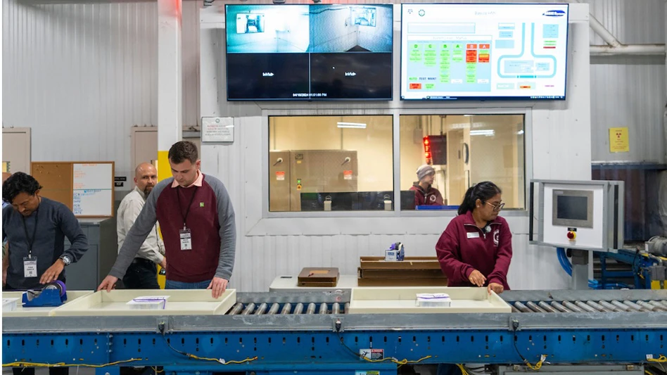 Workers in an industrial setting moving items along a conveyer belt