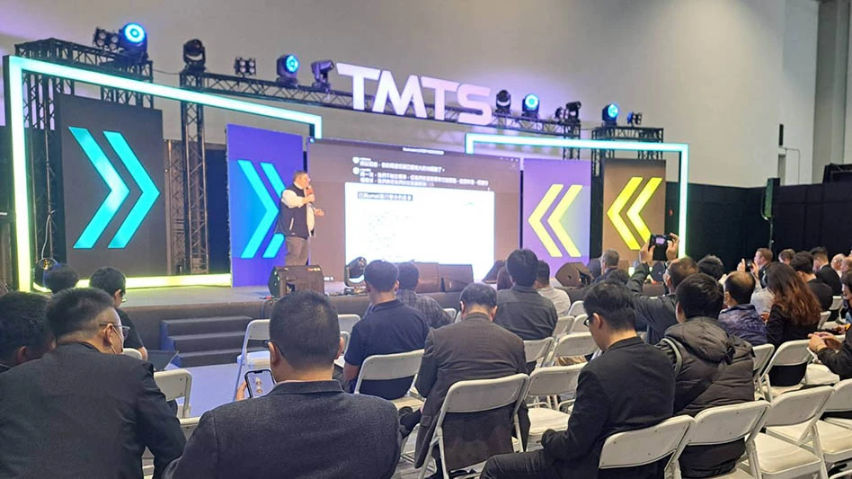 man giving a presentation in front of a seated crowd at a TMTS press briefing