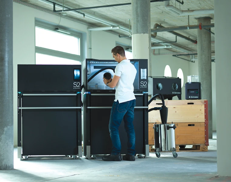 person standing in front of an additive manufacturing machine